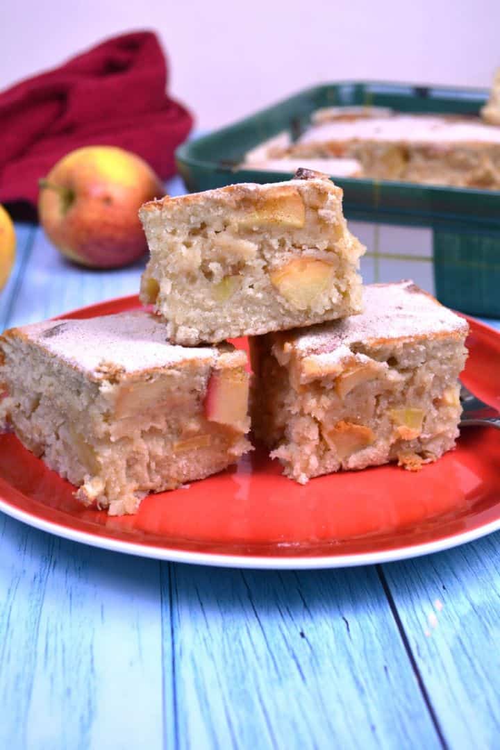 Freshly baked easy apple cake bars dusted with powdered sugar and served on a plate.