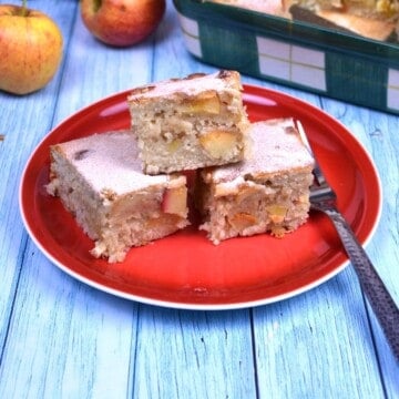 Freshly baked easy apple cake bars dusted with powdered sugar and served on a plate.