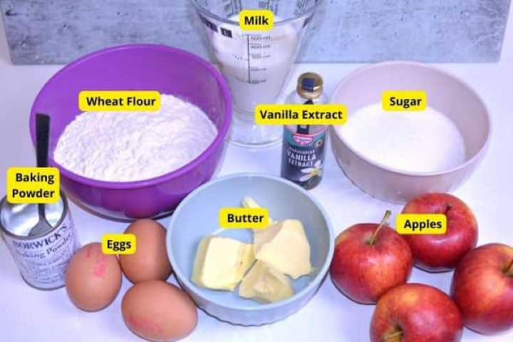 Ingredients for easy apple cake including fresh apples, eggs, flour, caster sugar, melted butter, milk, and cinnamon.