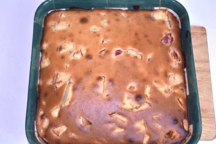 Golden-copper baked apple cake fresh from the oven cooling in a square ceramic dish.