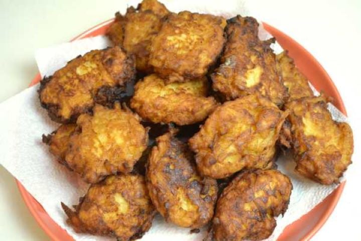 Freshly cooked golden apple fritters resting on paper towels to drain excess frying oil.