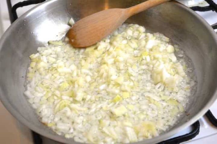 Sautéing the finely chopped onions in vegetable oil in a large pan until soft and translucent.