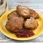 Authentic Hungarian cottage cheese donuts (Túrófánk) served with powdered sugar and plum jam on a yellow plate.