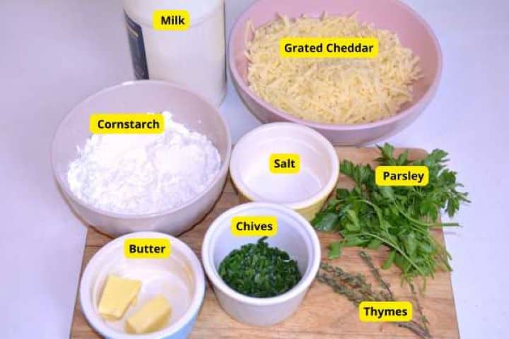 Ingredients Ingredients for homemade herbed cream cheese including milk, grated cheddar, butter, cornstarch, and fresh herbs.