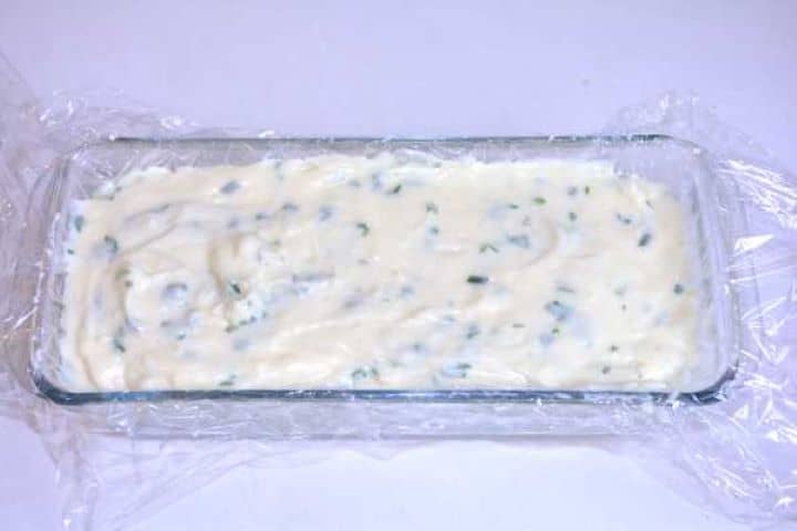 cooling Pouring warm herbed cream cheese into a cling film-lined glass loaf pan to chill and set.