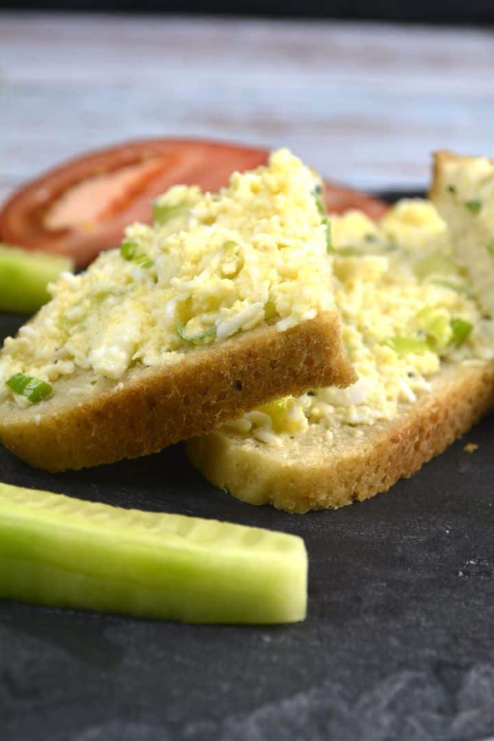 Creamy Hungarian egg salad spread smoothly onto sliced crusty sourdough bread and garnished with fresh chopped chives.