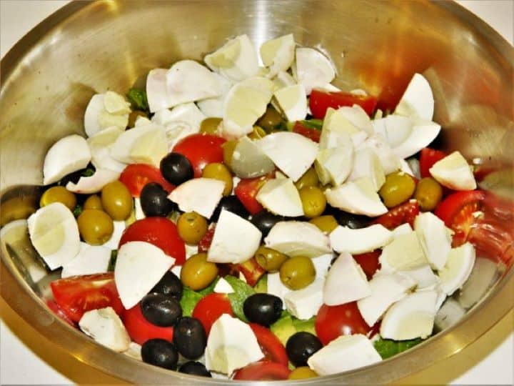 Quartered hard-boiled eggs layered into the bowl with fresh salad ingredients.