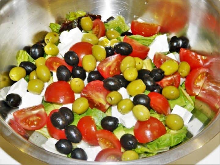 Pitted green and black olives added into the salad bowl.
