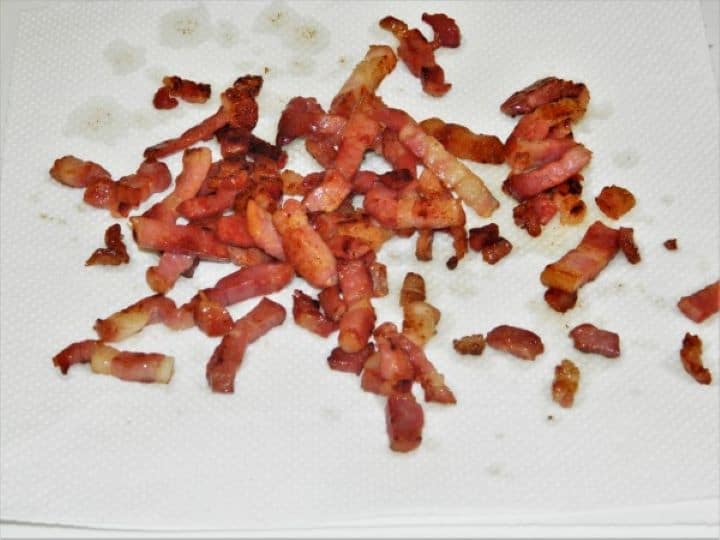 Crispy fried smoked bacon cooling and draining on a paper towel-lined plate.