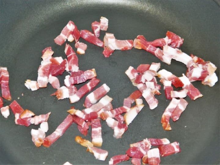 Frying chopped smoked bacon in a skillet until golden and crispy.