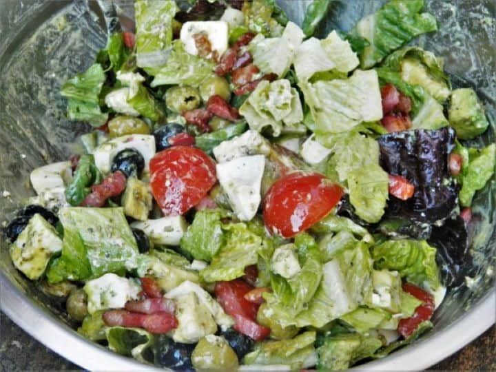 Tossed loaded tomato avocado egg salad with bacon ready to be served.