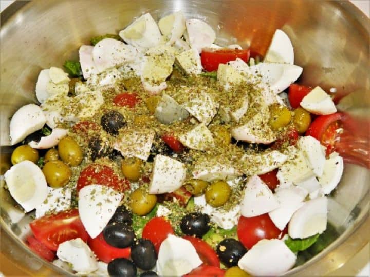 Sprinkling dried oregano, sea salt, and black pepper directly over the salad ingredients.