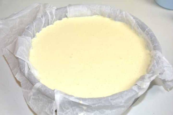 Pouring smooth Basque cheesecake batter into the parchment-lined springform pan.