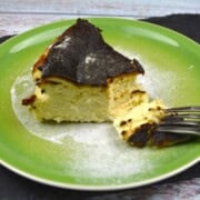 Authentic Basque burnt cheesecake slice with a deeply caramelized top serving on a green plate.