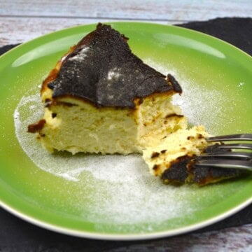 Authentic Basque burnt cheesecake slice with a deeply caramelized top serving on a green plate.