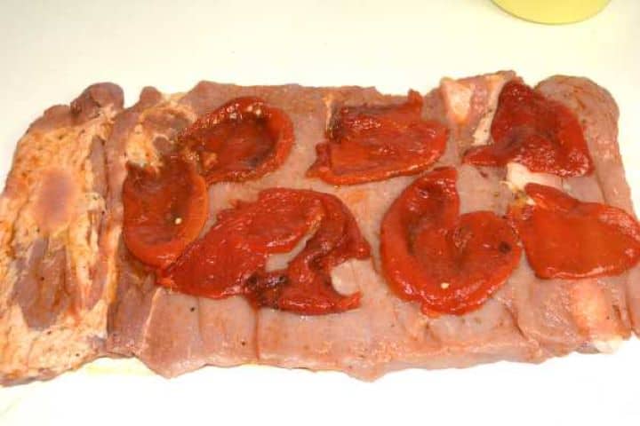 Roasted peppers is the first layer on the pork loin.