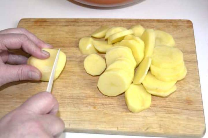 Thin sliced potatoes on the cutting board.