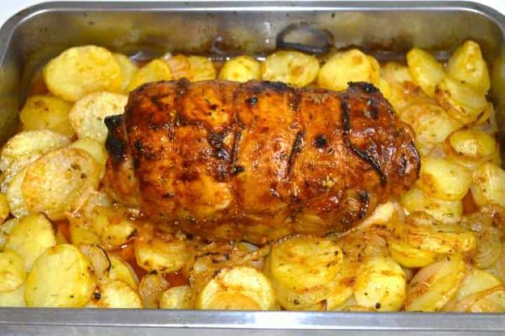 Brushing freshly baked ham and cheese stuffed pork roast with a final layer of glossy garlic-herb baste.
