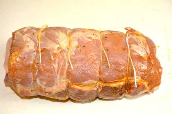Tightly rolled ham and cheese stuffed pork loin secured with butcher twine to seal the filling.
