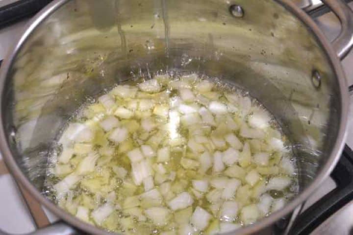 Sautéing diced onions and minced garlic in butter and oil in a large soup pot.