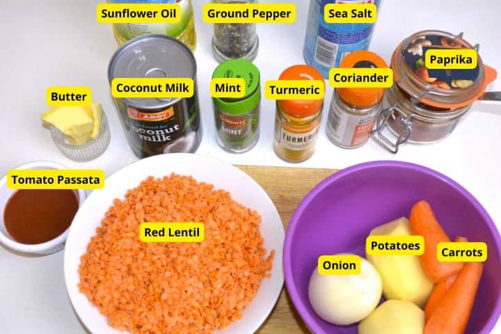 Raw ingredients for spiced carrot and red lentil soup including carrots, red lentils, potatoes, onion, garlic, and spices.