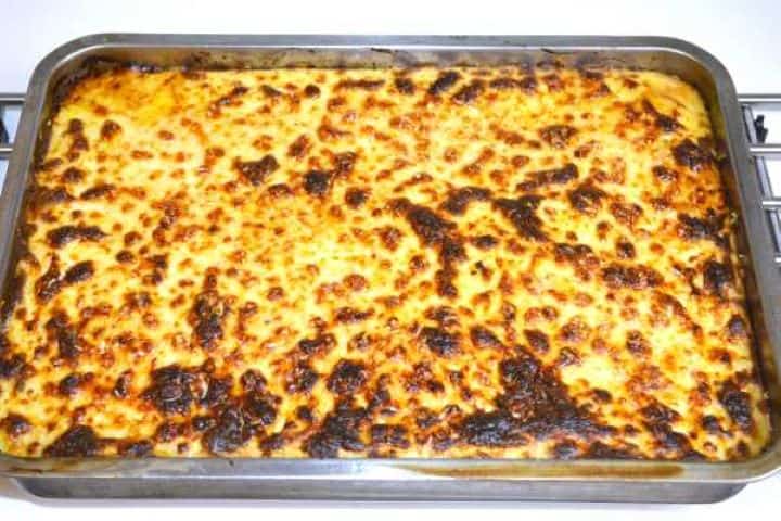 A golden brown, bubbly tray of Greek moussaka with eggplant and potatoes fresh from the oven.