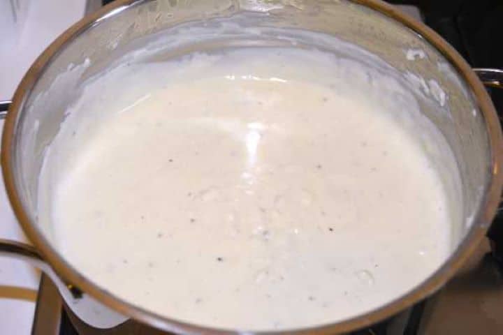 Whisking a creamy, velvety béchamel sauce with nutmeg for a moussaka topping.
