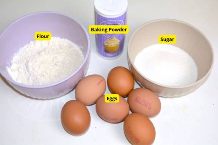 Baking ingredients for sponge cake including fresh eggs, all-purpose flour, sugar, and baking powder.