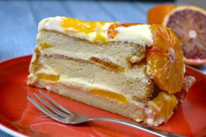 Close-up cross section of upside down orange cake showing sponge layers, citrus syrup, and pastry cream.