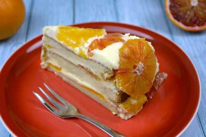 A slice of upside down orange cake with layered diplomat cream served on a red dessert plate.