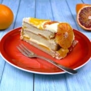 A slice of upside down orange cake with layered diplomat cream served on a red dessert plate.