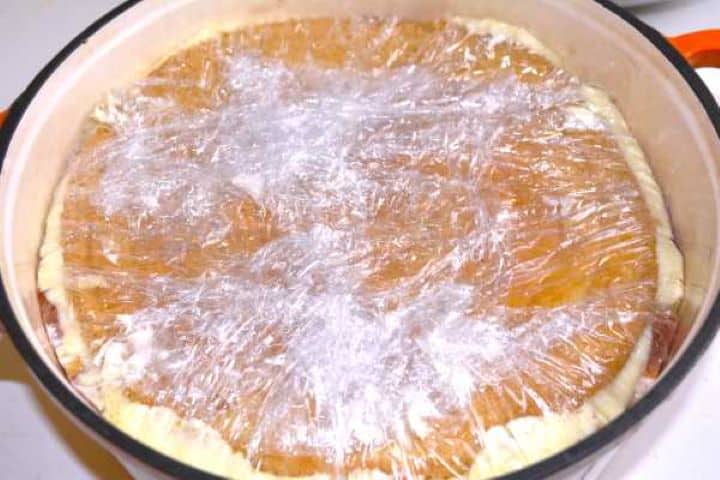 Assembled layers of sponge, orange slices, and diplomat cream inside a pot ready for chilling.