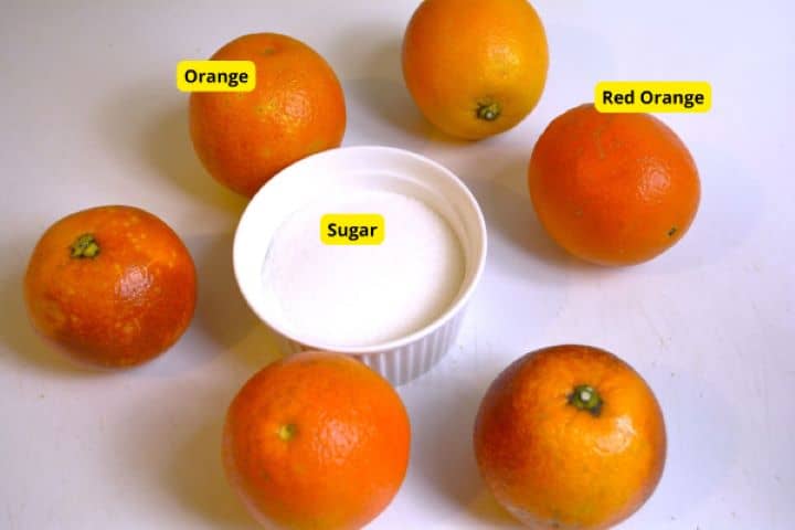 Fresh whole oranges and granulated sugar on a kitchen counter for macerating citrus.