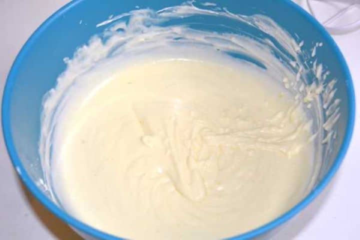 Gently folding cooled citrus custard into whipped heavy cream in a blue bowl.