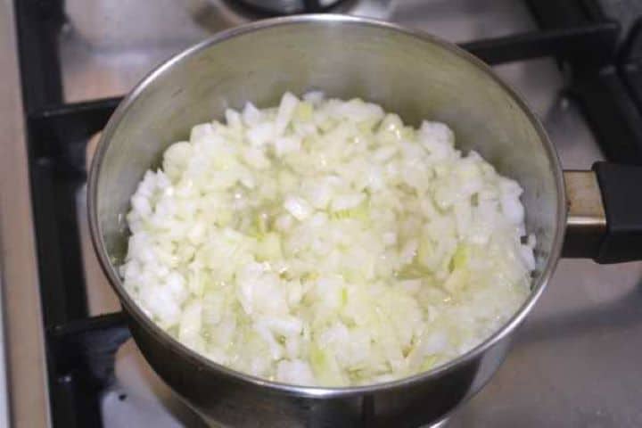 Finely chopped yellow onions sautéing in sunflower oil in a saucepan until soft and translucent.