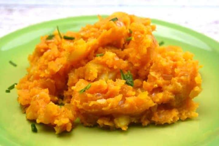 Close-up of easy 5-ingredient caramelized onion mashed potatoes garnished with chopped fresh chives on a green serving plate.