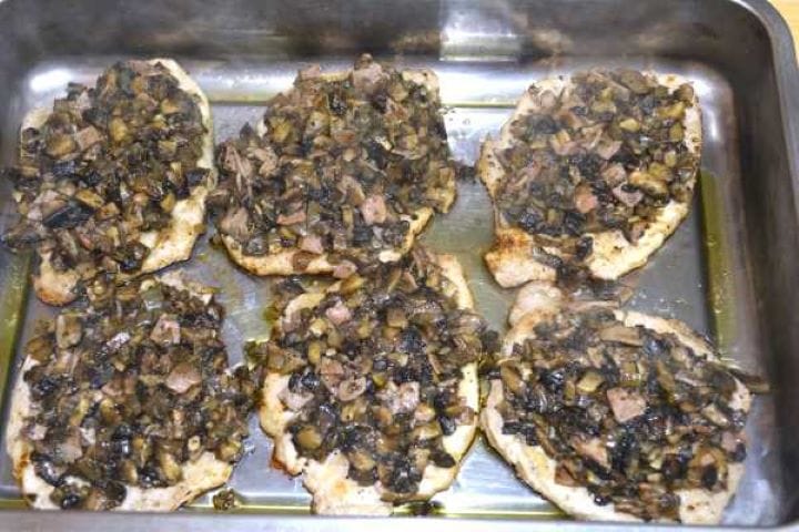 Spoonfuls of sautéed mushroom and ham topping evenly layered over seared pork chops.
