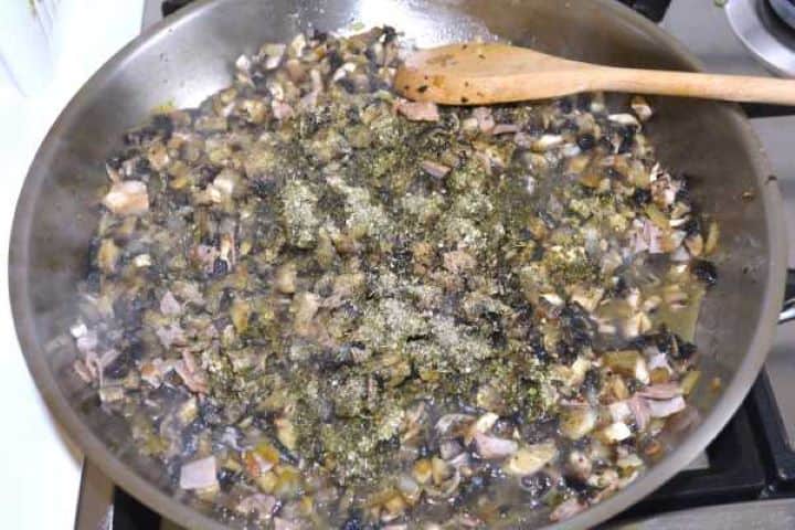 Adding chopped portobello mushrooms, marjoram, and seasoning to the skillet.