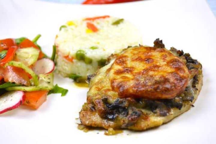 Tender cheesy pork chop served warm on a plate with fluffy buttered rice.