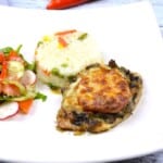 Juicy cheesy pork chops topped with melted mozzarella, served on a white plate with steamed rice and fresh summer salad.