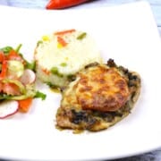 Juicy cheesy pork chops topped with melted mozzarella, served on a white plate with steamed rice and fresh summer salad.