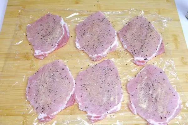 Cheesy Pork Chops-Tenderized and Seasoned Pork Chops on the Chopping Board