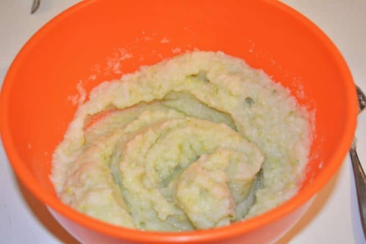 Smooth and silky blended cauliflower puree in an orange mixing bowl.