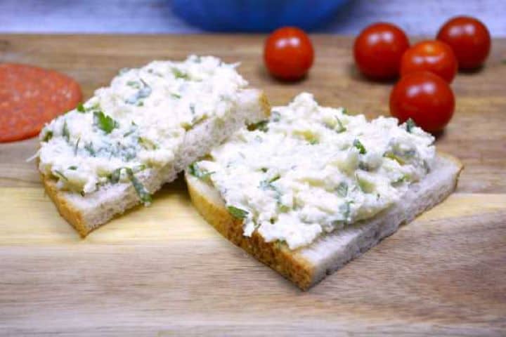 Chilled cauliflower dip spread over sourdough bread with cherry tomatoes and dry salami on a breakfast platter.