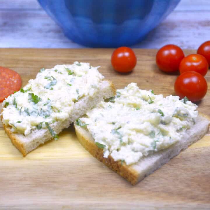 Creamy cauliflower spread served on rustic crusty bread with sliced salami and fresh cherry tomatoes.