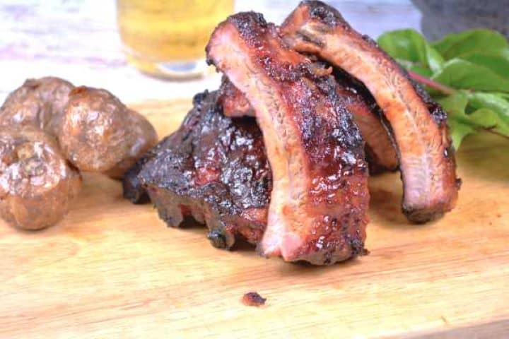Honey glazed pork ribs served on chopping board.