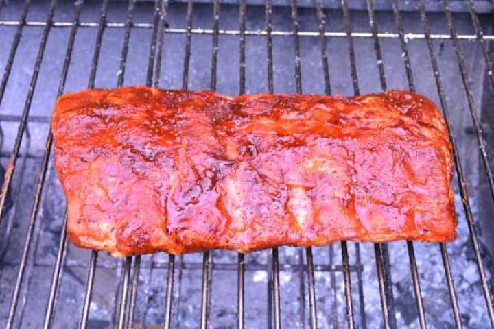 Basting tender grilled ribs with a glossy honey paprika glaze over hot charcoal grates.
