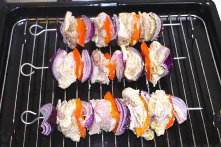 Assembled chicken skewers placed on an elevated wire rack over a baking sheet ready for the oven.