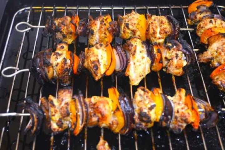 Charred, golden oven baked chicken skewers resting on a baking sheet.