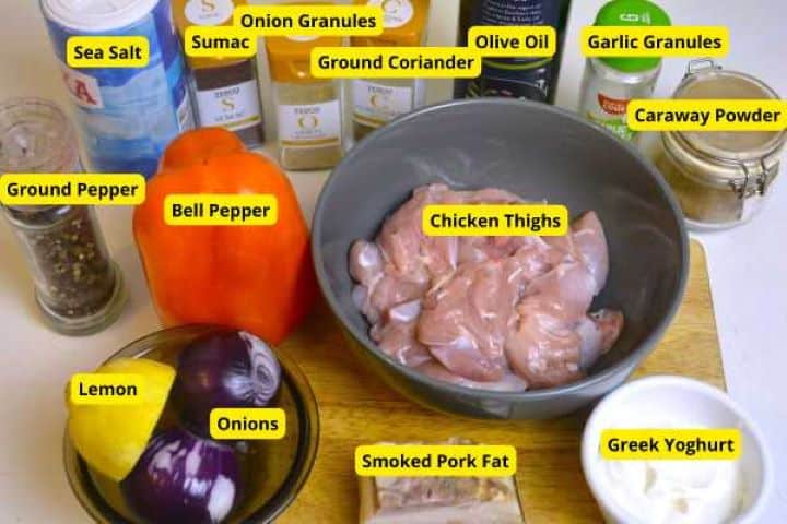 An organized flat lay or arrangement of all the fresh ingredients needed for the oven cooked chicken kebabs recipe, including chicken thighs, peppers, onions, Greek yogurt, olive oil, and various spices.
